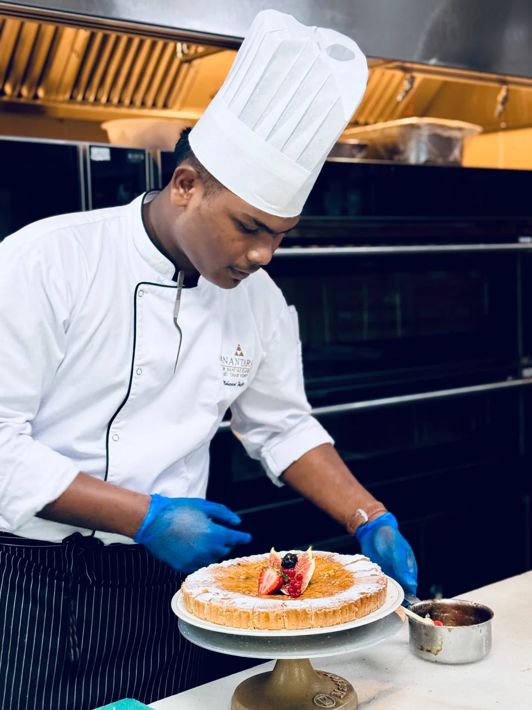 Mohamed Thawfiq carefully finishing a fruit tart in the kitchen